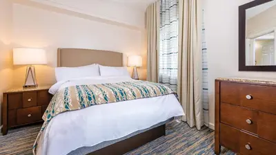 a bedroom with a bed and a dresser and a mirror at Marriott's Cypress Harbour 2BR Apartment with Resort Access in Orlando