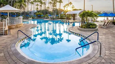 a large swimming pool with palm trees and blue umbrellas at Marriott's Cypress Harbour 2BR Apartment with Resort Access in Orlando