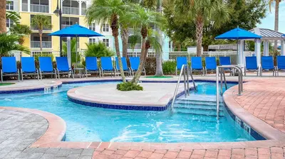 a swimming pool with blue chairs and blue umbrellas at Marriott's Harbour Lake 1BR Apartment with Resort Access in Orlando