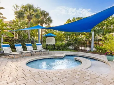 a pool with chairs and umbrellas on a patio at Marriott's Royal Palms 2BR Apartment with Resort Access in Orlando