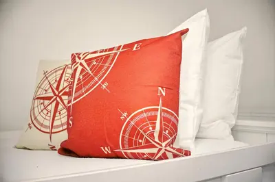 a red pillow on a bed with three white pillows at Vibrant 5BR Family Retreat in Storey Lake in Kissimmee