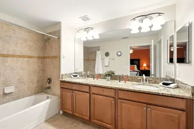 a bathroom with a tub and a sink and a tub and a mirror at Vibrant 5BR Family Retreat in Storey Lake in Kissimmee