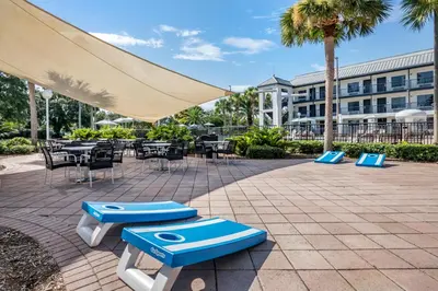 a patio with tables and chairs and a large umbrella at voco Kissimmee Orlando by IHG in Orlando
