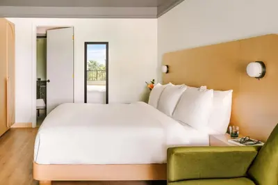 a bedroom with a large white bed and a green chair at voco Kissimmee Orlando by IHG in Orlando