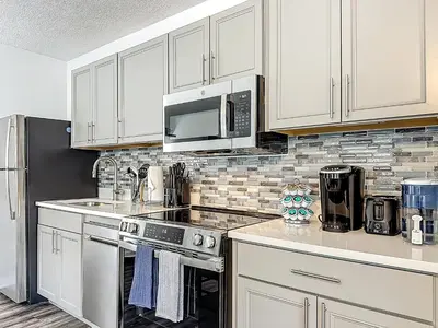 a kitchen with white cabinets and a stove and microwave at Comfy Studio Farm Stay in Orlando