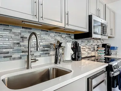 a kitchen with a stainless steel sink and white cabinets at Comfy Studio Farm Stay in Orlando