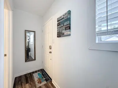a hallway with white walls and a mirror on the wall at Comfy Studio Farm Stay in Orlando