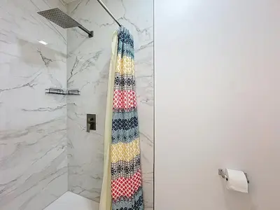 a bathroom with a shower with a tie on the wall at Comfy Studio Farm Stay in Orlando