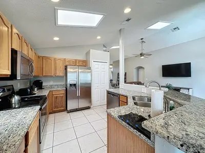 a large kitchen with stainless steel appliances and wooden cabinets at Casa del Sol at Indian Creek Four Corners villa in Kissimmee