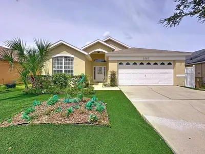 a house with a flower bed in front of a driveway at Casa del Sol at Indian Creek Four Corners villa in Kissimmee