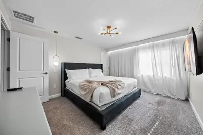 a bedroom with a bed with a black headboard and a window at Brand NEW 05 Bedrooms4 Baths At Storey Lake in Kissimmee