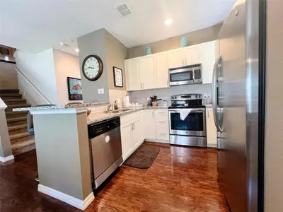 a kitchen with white cabinets and a stainless steel refrigerator at 4 Bedrooms 3 Bathrooms Lucaya 10-108 in Kissimmee