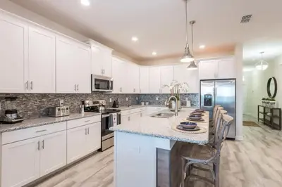 a kitchen with white cabinets and a marble counter top at Refúgio de Luxo 6 quartos c/ piscina aquecida in Kissimmee