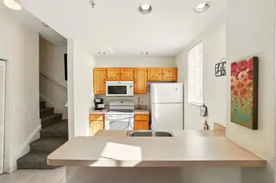 a kitchen with wooden cabinets and a white refrigerator at Your Orlando Escape - Gated Resort with Amenities in Kissimmee
