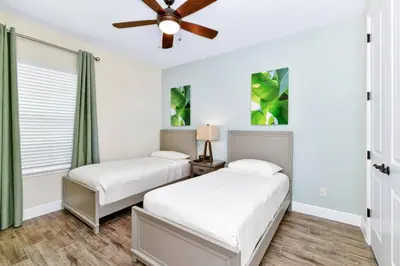 two beds in a bedroom with a ceiling fan at Paradise Breeze Cottage By Shine Villas Margaritaville Resort Orlando in Orlando