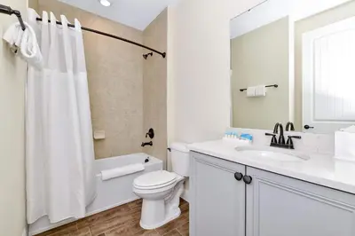 a white bathroom with a toilet and a sink at Paradise Breeze Cottage By Shine Villas Margaritaville Resort Orlando in Orlando
