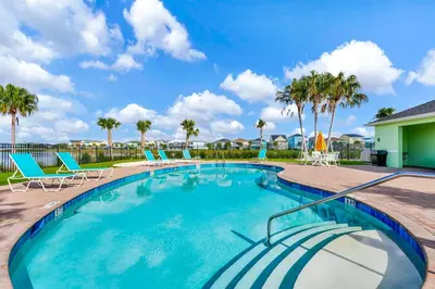 a swimming pool with chairs and palm trees at Paradise Breeze Cottage By Shine Villas Margaritaville Resort Orlando in Orlando