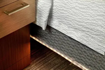 a corner of a bed next to a wooden cabinet at Courtyard by Marriott Orlando Lake Nona in Orlando