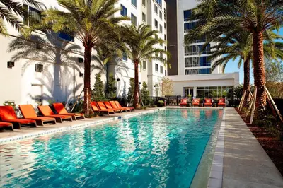 a swimming pool with orange chairs and palm trees at Residence Inn by Marriott Orlando Lake Nona in Orlando