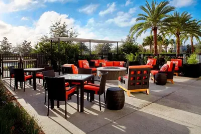 a patio with tables and chairs and palm trees at Residence Inn by Marriott Orlando Lake Nona in Orlando