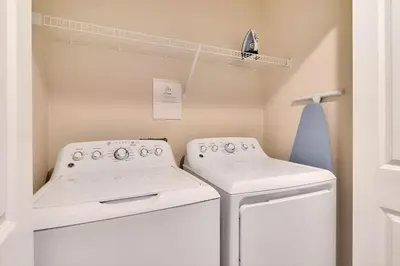 a laundry room with two washing machines and a shelf at Go08 - STOREY LAKE in Kissimmee