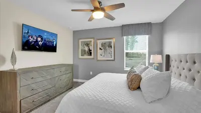 a bedroom with a bed with a ceiling fan and a dresser at Parfect Paradise in Orlando