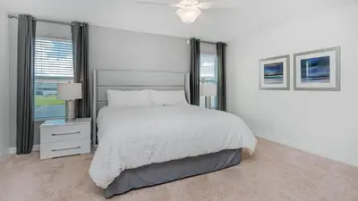 a white bedroom with a large bed and windows at Storey Lake Villa in Kissimmee