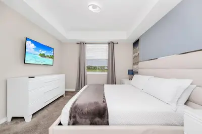 a white bedroom with a bed and a window at 2BR Family Condo Near Disney, Universal and More in Kissimmee