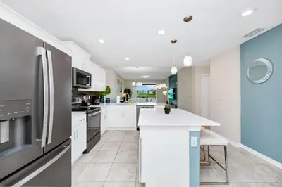a kitchen with white cabinets and a refrigerator at 2BR Family Condo Near Disney, Universal and More in Kissimmee