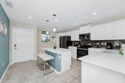 a kitchen with white cabinets and a blue island at 2BR Family Condo Near Disney, Universal and More in Kissimmee