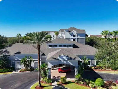 a large white house with a palm tree at Comfy Condo near Disney-Free Shuttle to Parks in Orlando