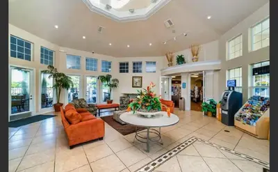 a large living room with orange chairs and a table at Condo Disney Universal Epic Pool in Kissimmee