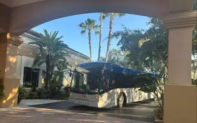 a bus parked in front of a building with palm trees at Cozy Condo near Disney World with Shuttle to parks in Orlando