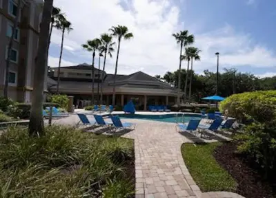 a swimming pool with chairs and a building and palm trees at Inspiration condo near Disney with free shuttle in Orlando
