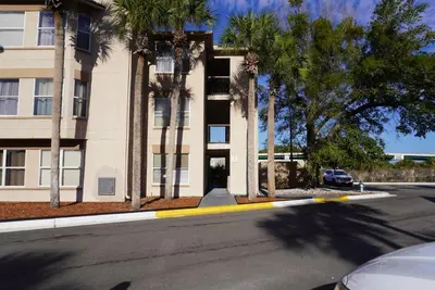 a building with palm trees in front of a street at Condo 2 Queen beds-Disney-Universal in Orlando