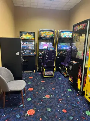 a room with four video game machines and a chair at Renovated Condo near Disney Free Shuttle to Parks in Orlando
