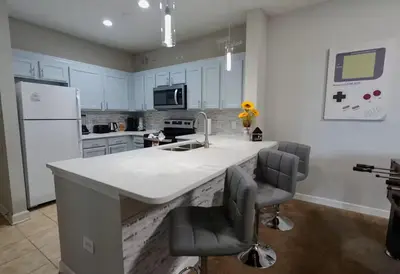 a kitchen with a large white counter and two chairs at Amazing Condo near Disney in Kissimmee