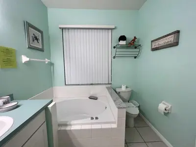 a bathroom with a tub and a toilet and a sink at Villa near Disney Jacuzzi Pool 4bed-3baths in Kissimmee