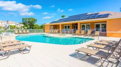 a swimming pool with solar panels on a house at Contemporary 4BR Townhome with Pool & Themed Rooms in Orlando