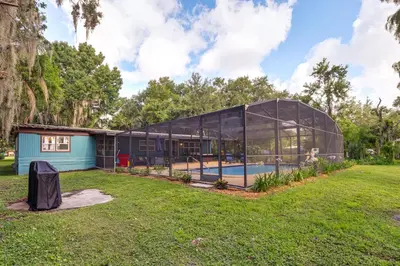 a glass house with a pool in a yard at Lakefront Home with Hot Tub and Dock in Orlando! in Orlando