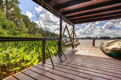a wooden deck with a boat on the water at Lakefront Home with Hot Tub and Dock in Orlando! in Orlando