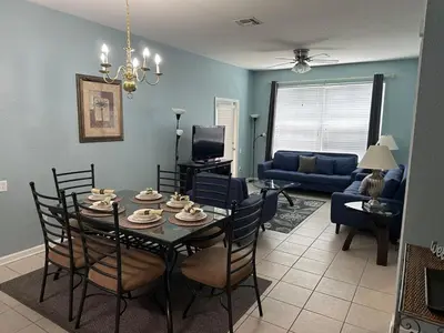 a dining room and living room with a table and chairs at PalmTree Oasis 3 bedroom Condo at Windsor Hills in Orlando