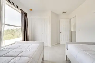 a white bedroom with two beds and a large window at Kissimmee Resort-Style Home Close to Shops and Eats in Kissimmee