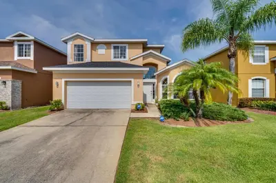 a house with a garage and a palm tree at Kissimmee Resort-Style Home Close to Shops and Eats in Kissimmee