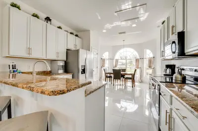 a kitchen with white cabinets and marble counter tops at Kissimmee Resort-Style Home Close to Shops and Eats in Kissimmee