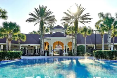 a large swimming pool in front of a building with palm trees at 6 Bedroom Villa located in Windsor Hills 3 miles to Disney Free Heated Pool & Spa Game Room with PS5! in Orlando