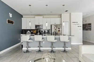 a kitchen with white cabinets and a bar with stools at Comfort Stay with Pool Near Attractions in Kissimmee