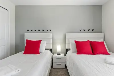 two beds with red pillows in a bedroom at Comfort Stay with Pool Near Attractions in Kissimmee