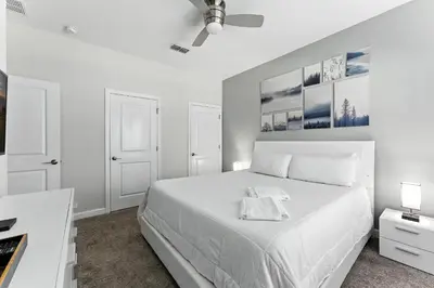 a white bedroom with a white bed and two lamps at Comfort Stay with Pool Near Attractions in Kissimmee