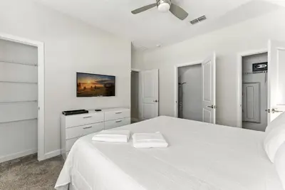 a white bedroom with a large white bed with two white towels at Comfort Stay with Pool Near Attractions in Kissimmee
